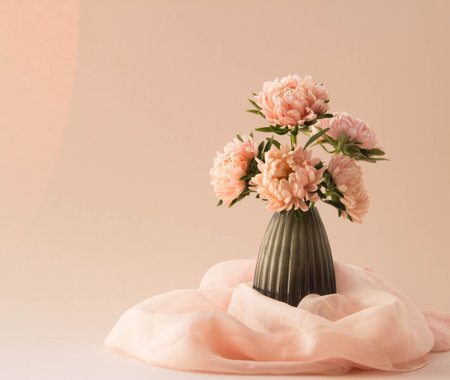 Bouquet of asters flowers in vase. Elegant arrangement of pink garden flowers with silk scarf on pastel background.の写真素材