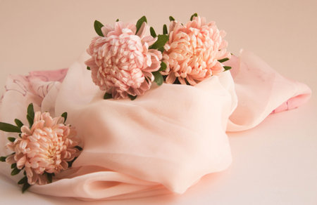 Asters flowers with silk scarf. Elegant floral arrangement of garden flowers on pink background.