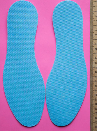 Pair of blue insoles on a pink background. top view.の写真素材