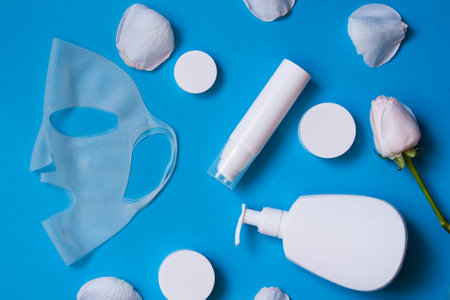 Cosmetics for face and body care with cosmetic silicone mask on blue background, mockup. health care concept. top view.の写真素材