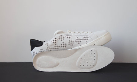 Leather orthopedic insole and white sport shoe on black white background. Foot care accessories.の写真素材