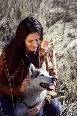 Girl husky is scratching behind the ear and smiles . Spring field.の写真素材