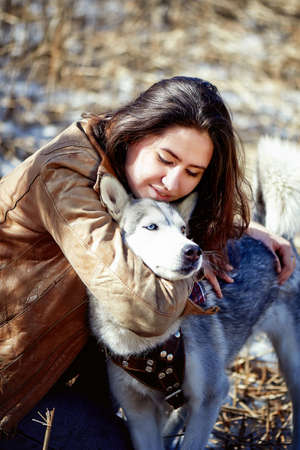 Beautiful woman with husky outdoors.Happy brunette woman with smiling siberian husky dog, sitting in...