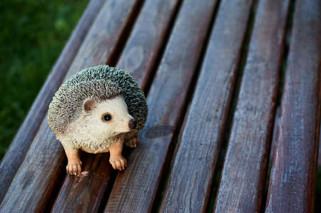 naturalistic statuette of a hedgehog standing on garden bench