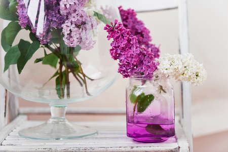 Bunch of fresh lilac flowers in glass vase close up isolated on white backgroundの写真素材