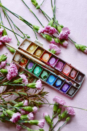 The workplace of the artist. Paint brush and pink carnations Still life composition of artistic workplaceの写真素材