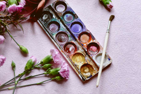 The workplace of the artist. Paint brush and pink carnations Still life composition of artistic workplaceの写真素材
