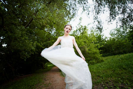 Beautiful girl walking in a white dress in a flowing dress. Dynamics. Boho style in full growthの写真素材