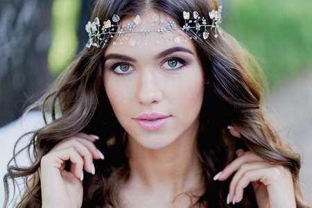 Close-up portrait of beautiful young brunette European type, with long curly hair and the decoration on the hairの写真素材