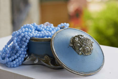 Blue jewelry Box with the silver moldings on the legs, with blue beads on a string. Close, bokehの写真素材