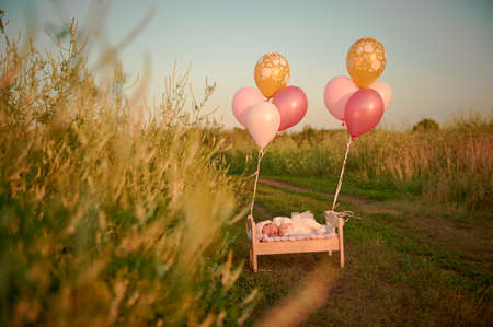 A tiny baby asleep in his crib in lace bonnet A tiny baby asleep in his crib in lace cap and flies away with balloonsの写真素材
