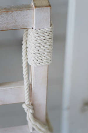 The rope is coiled around a white wooden support chairの写真素材