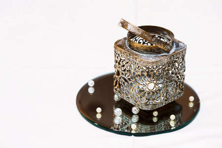 A Golden candlestick with a candle on a mirrored stand and beads. Decoration of wedding tableの写真素材