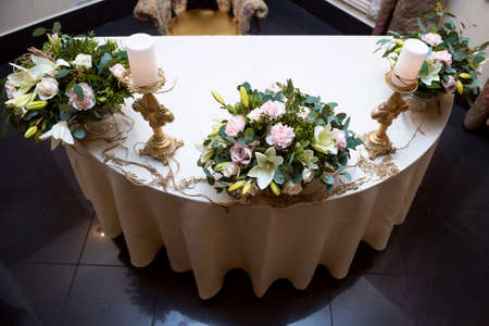 A Golden candlestick with a candle. Decoration of wedding table. Three flower arrangements.の写真素材