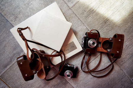 Bright photobook with leather light cover lying on the floor. The next two camera in leather brown...