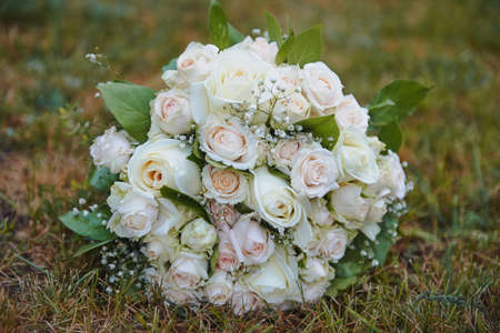 Wedding Bridal bouquet of cream roses with baby's breath round shape on a grass background. Floralの写真素材