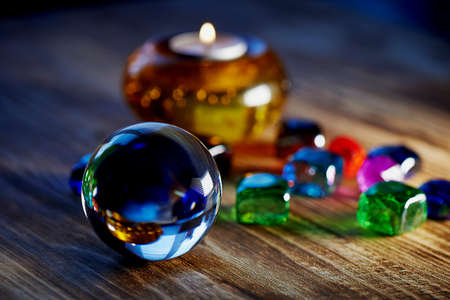 Mysterious cozy glass ball, multi-colored beads, and a candle in a candlestick. Intimacy