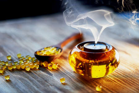 Candle in glass orange candle holder with colorful beads, seduta. Smoke risesの写真素材