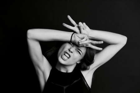 Young beautiful girl with long hair. The gesture of a goat. BWの写真素材