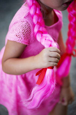 Children handle holds a braid of pink hair. Festiveの写真素材