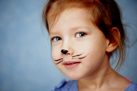 Baby 3 years with face painting of a cat, meowing and smiling