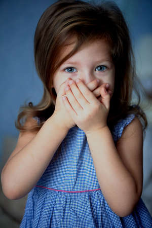 Speak no evil . Baby covers mouth with handsの写真素材