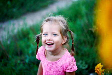 Beautiful blue-eyed girl with two pigtails laughs.の写真素材