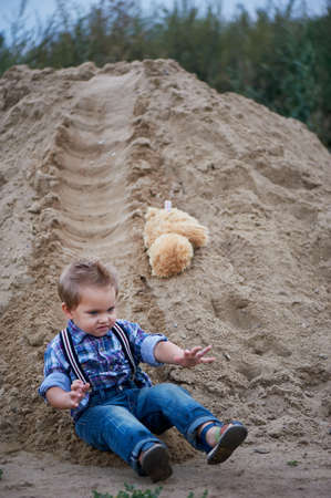 Little cute boy riding a roller coaster of sand on the bottom. Memories of childhood and carefreeの写真素材