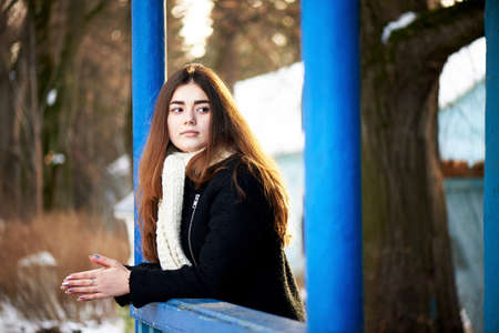 Young girl looking at the camera. Long dark hair, scarf, white chunky knit. Lifestyleの写真素材
