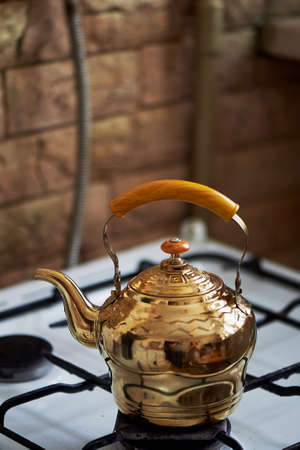Copper kettle stands on an old vintage plate. Kitchenの写真素材