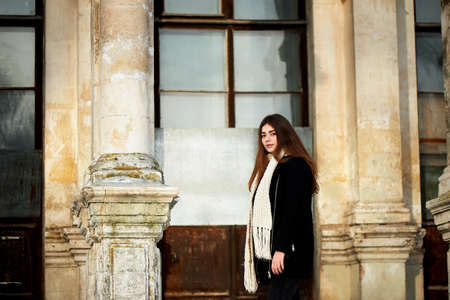 Young girl looking at the camera. Long dark hair, scarf, white chunky knit. Lifestyle
