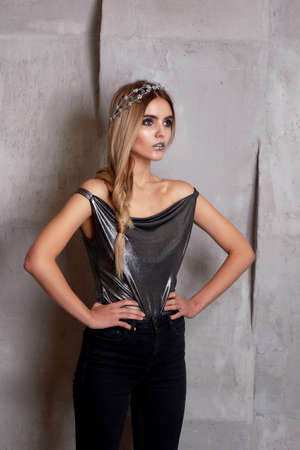 Beautiful girl model in the Studio shooting beauty. Silver makeup, hair in a sloppy spit, silver top.の写真素材
