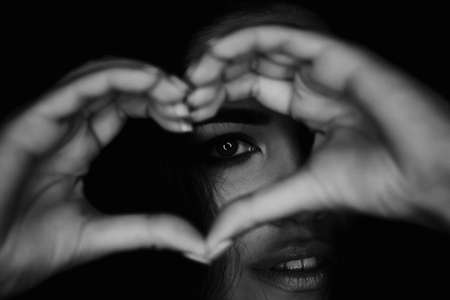 Beautiful elegant girl holding hands in front of face heart shaped. Lips slightly parted. Beautiful eyes.Valentines dayの写真素材