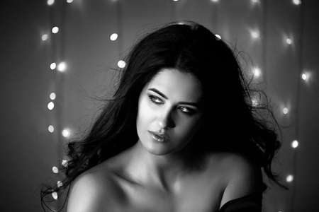Portrait of a beautiful smiling brunette with long hair. Studio photography , bokeh light bulbs.Black and whiteの写真素材