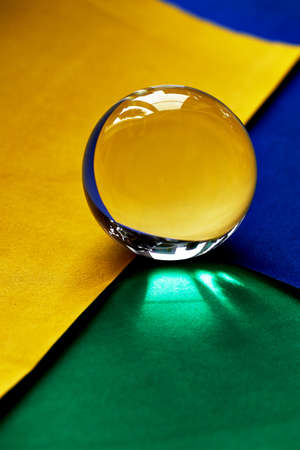 Glass globe or drop of water on a background of green, yellow and blue velvet paper. Clean and Shine