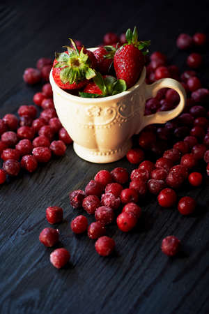 Bowl of juicy strawberries on a dark wood background.On top of Rossana berry. Cherry, strawberry,...