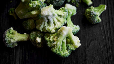 Frozen broccoli on a black wooden background . Vegetarian lifestyle, healthy eatingの写真素材