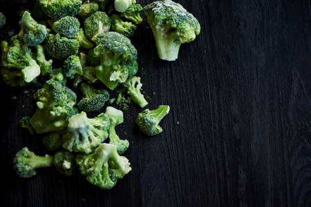 Frozen broccoli on a black wooden background . Vegetarian lifestyle, healthy eatingの写真素材
