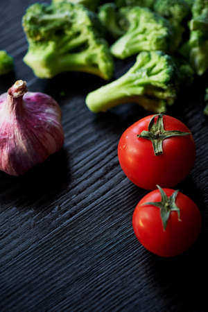 Broccoli, tomatoes and garlic lying on a dark background. Healthy eating.Vegetarianism. Fresh vitaminsの写真素材