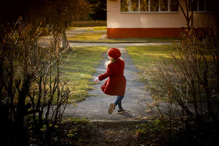 Baby 3 years with long hair. In a red beret and coat spinning in the street , in the rays of the sun. The state of happiness. Childhoodの写真素材