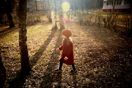 Baby 3 years with long hair. In a red beret and coat spinning in the street , in the rays of the sun. The state of happiness. Childhoodの写真素材