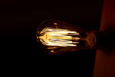 Edison light bulb hanging on a long wire. Cozy warm yellow light. Retro
