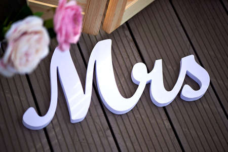 inscription Mrs as decor at the wedding against the dark boards with pink flowersの写真素材