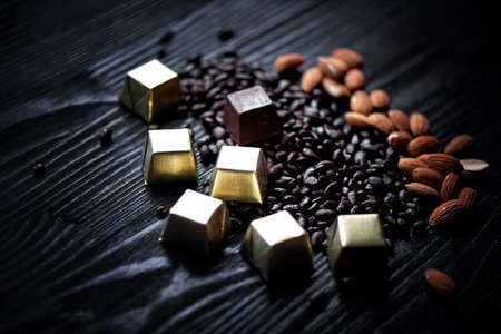 Candy in Golden foil, almonds and sunflower seeds in chocolate lying on a dark background. Studioの写真素材