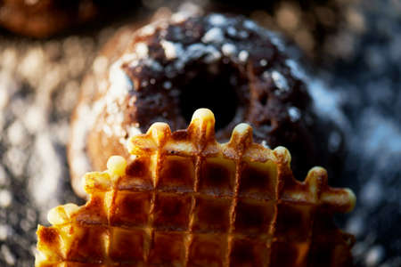 Lush fresh chocolate muffins sprinkled with powdered sugar, lay against the dark wood. Round Belgian waffles.Studioの写真素材