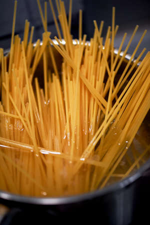 Spaghetti from durum wheat are cooked in a metal pot on the fire. Closeの写真素材