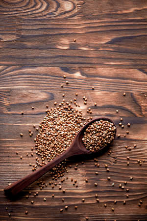 Spoon with buckwheat on the background of dark burnt wood.Rustic styleの写真素材