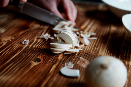 People cut mushrooms with a knife. The slices are adjacent. Wooden surfaceの写真素材