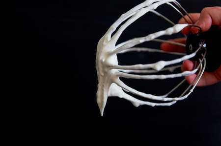 Metal whisk from the mixer with the remnants of whipped cream.cookingの写真素材