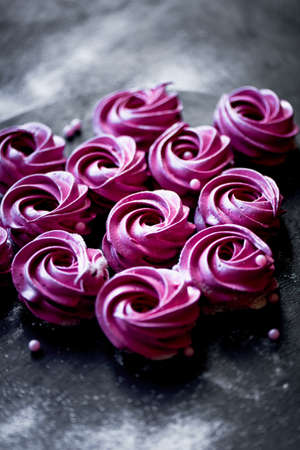 Many purple marshmallow on a dark surface. A contrasting picture.A work of culinary art